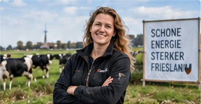 Vrouw met gekruiste armen in een weiland met koeien, naast een bord met de tekst schone energie, sterker Friesland.